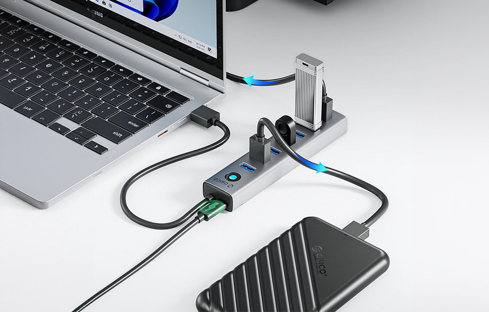 USB-C HUB ORICO 7u1 crni priključen na laptop sa više povezanih uređaja.
