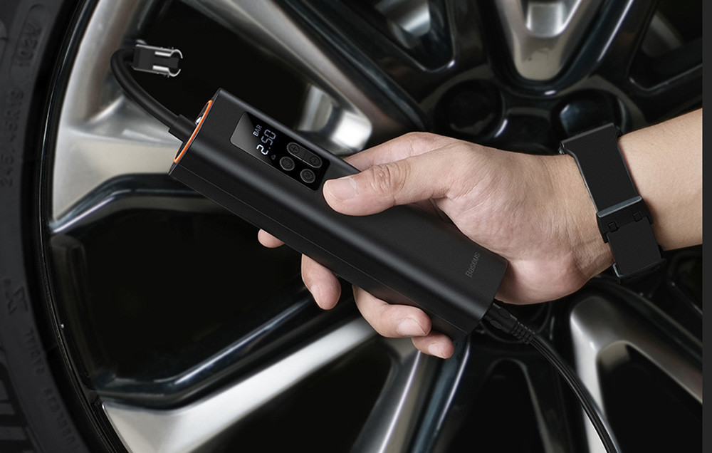 Mini auto kompresor BASEUS 12V u ruci, priključen na automobilsku gumu.